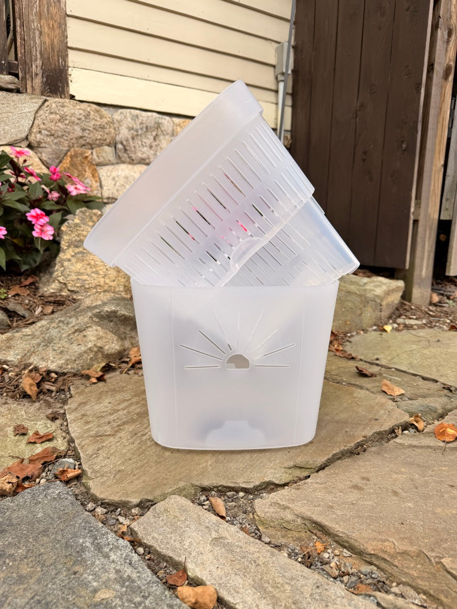 The slotted inner pot lifting out of the clear outer pot that holds the water reservoir