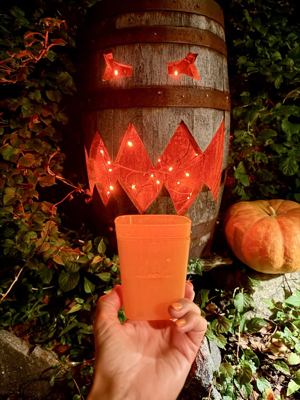A 3 inch Pumpkin Sugar planter held up in front of a lit jack-o'-lantern barrel