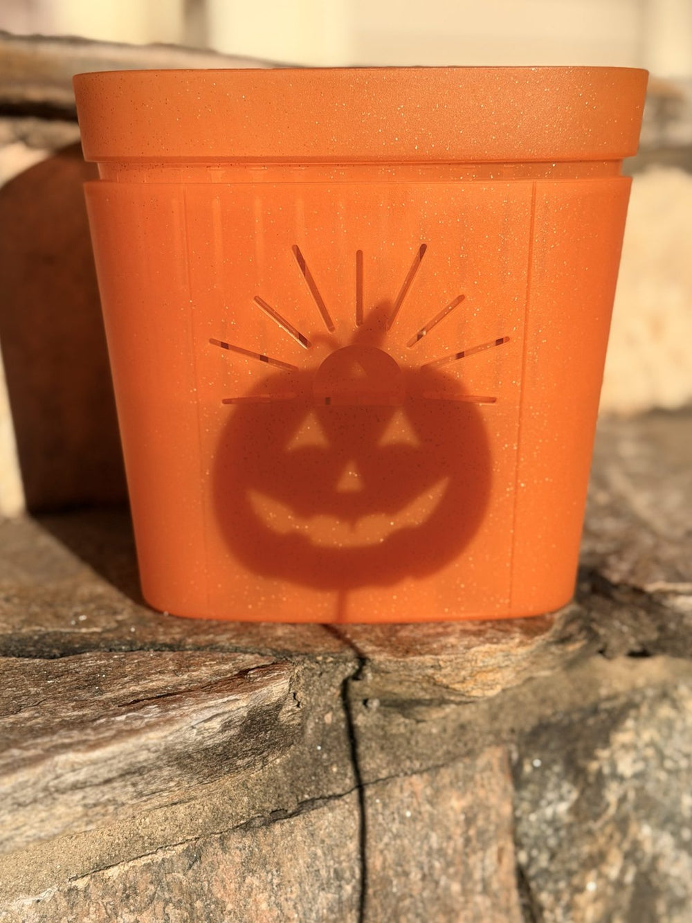 A jack-o'-lantern shadow glowing through an 8 inch Pumpkin Sugar planter