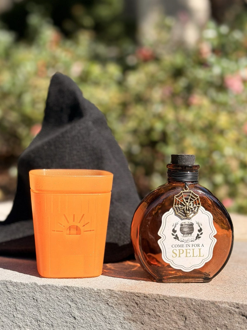 A 3 inch Pumpkin Sugar planter beside a witch hat and a potion bottle